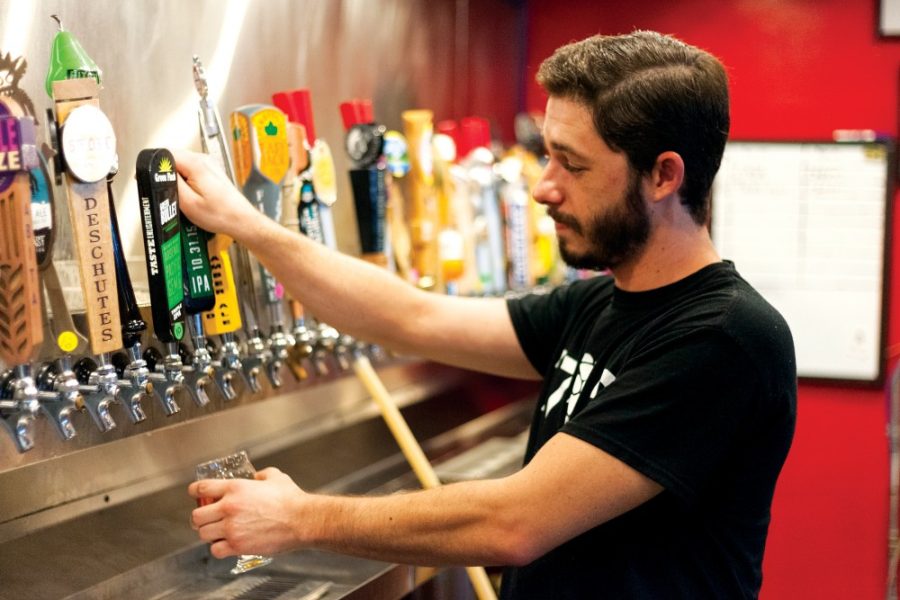 John Langan, a server at 1702 Pizza & Beer, pours a beer for a customer. The pizzeria and bar is located at 1702 E. Speedway Blvd., where Langan shared stories of his experiences as a bartender at 1702 and other restaurants around town.