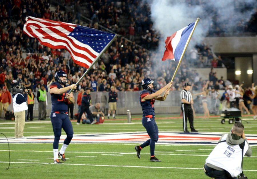 Arizona kicker Casey Skowron (41) waves the French flag while Arizona punter Drew Riggleman (39) hoists the U.S. flag before the Wildcats win over Utah at Arizona Stadium on Saturday, Nov. 14. The special teams duo has had great success this season and were honored for Senior Night. 
