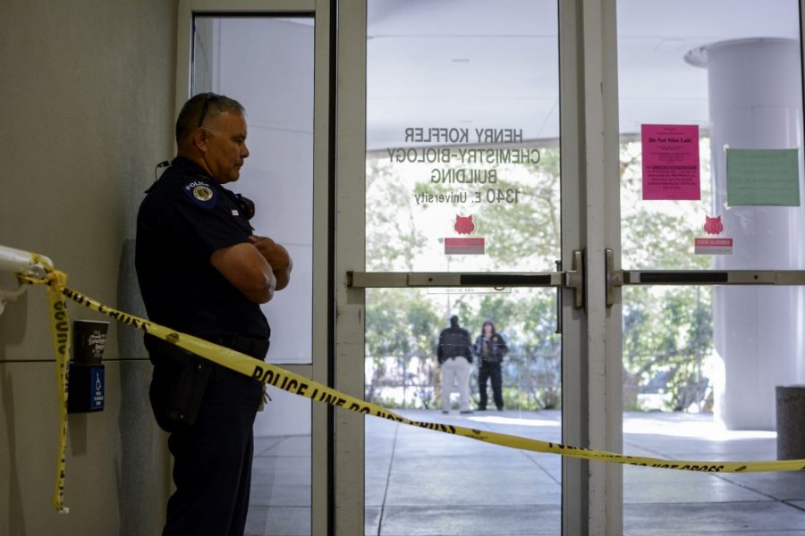 Officer Ugalde stands guard inside a door to the Koffler building on the UA campus that was cordoned off on Tuesday, Jan. 26. Police were responding to an incident in which a body was found near the building.