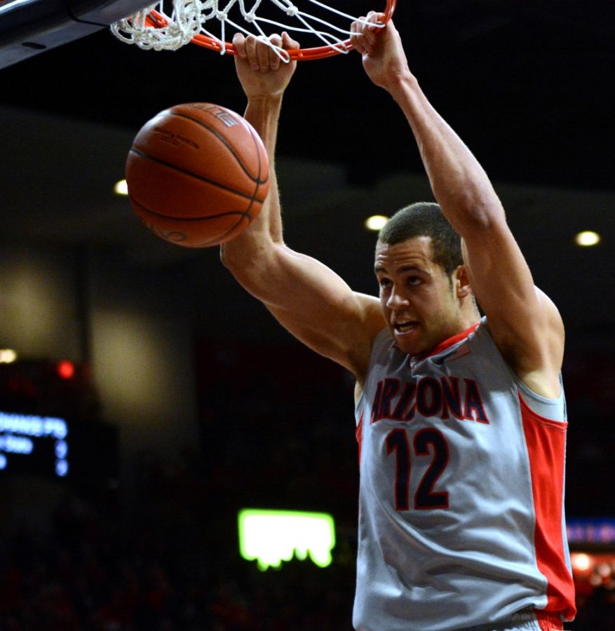 Arizona guard Ryan Anderson (12) hangs on to the rim after a dunk in McKale Center while playing against Oregon State on Saturday, Jan. 30. Anderson finished with 22 points and 15 rebounds in a win over Washington in Seattle.