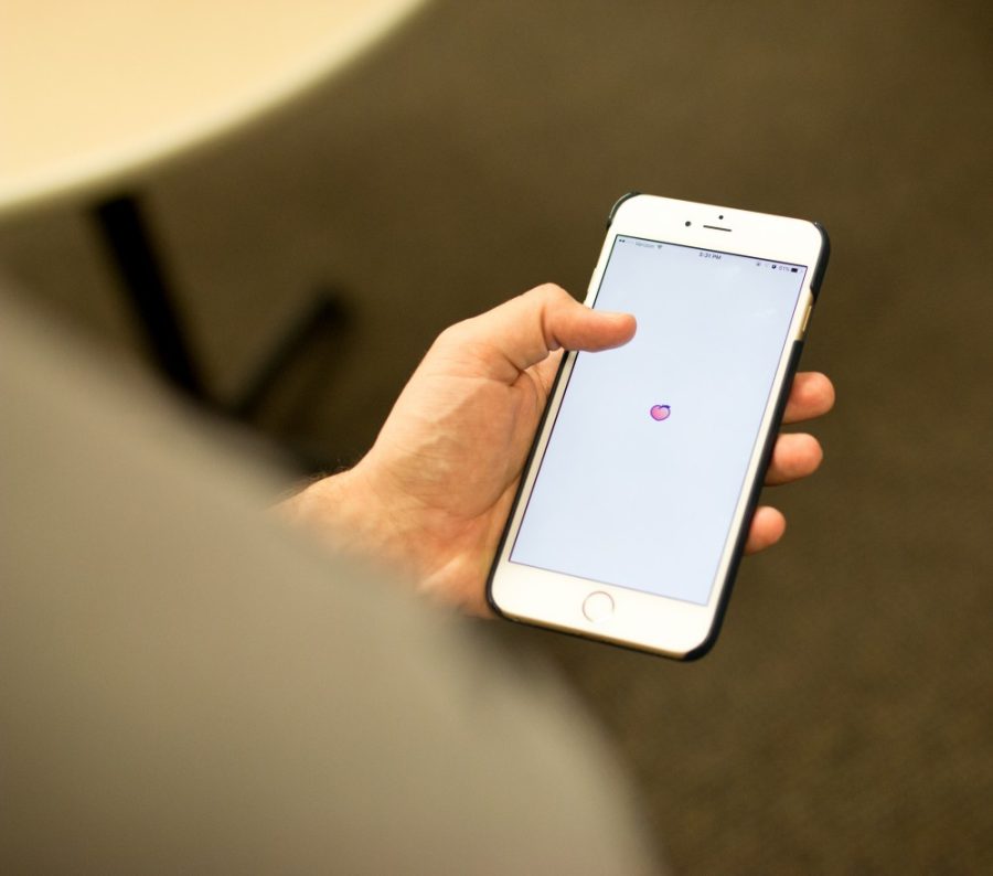 Photo illustration of a student opening the Peach app onto the splash screen. The app is intended to fill a social media void with college students.