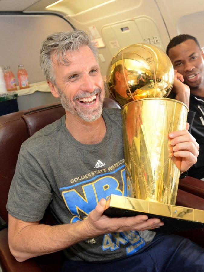Bruce Fraser of the Golden State Warriors holds the NBA trophy on a plane as the team travels home from Cleveland after winning the 2015 NBA Finals on June 17, 2015 in Oakland, California. Fraser played for Arizona from 1984-1987. 