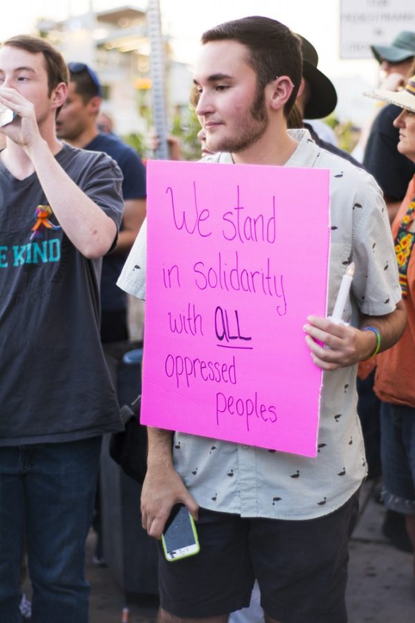 Tony Bishop holds up a sign in solidarity at a vigil for the Orlando victims on Sunday, June 12, 2016 in Tucson, Ariz. Bishop identifies as transgender.