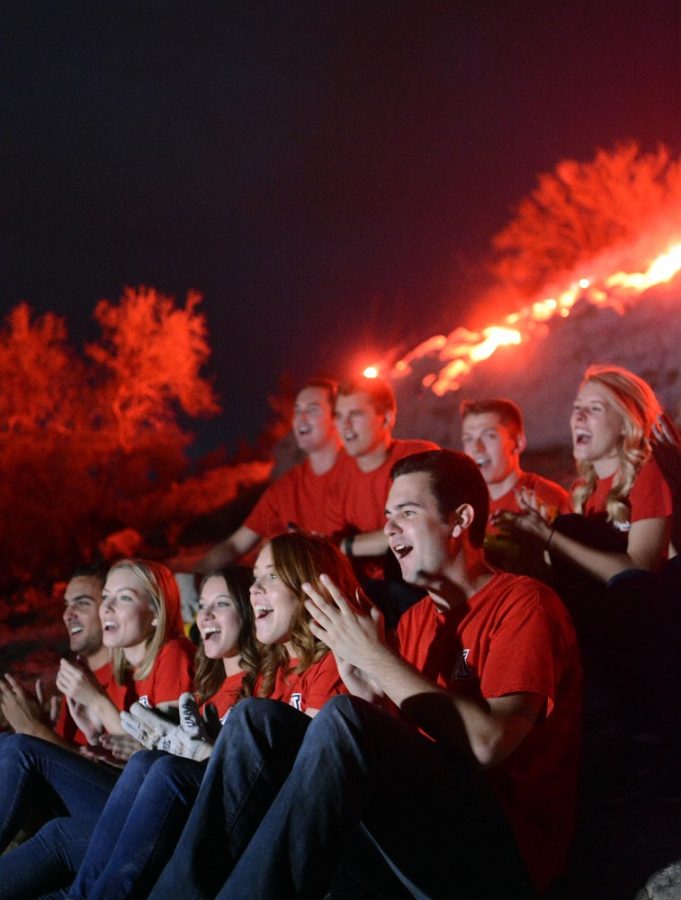 The Bobcats senior honorary claps while singing "Bear Down Arizona," the UA fight song, after lighting the "A" on "A" Mountain with flares during the annual ceremony on Sunday, Oct. 23, 2016.