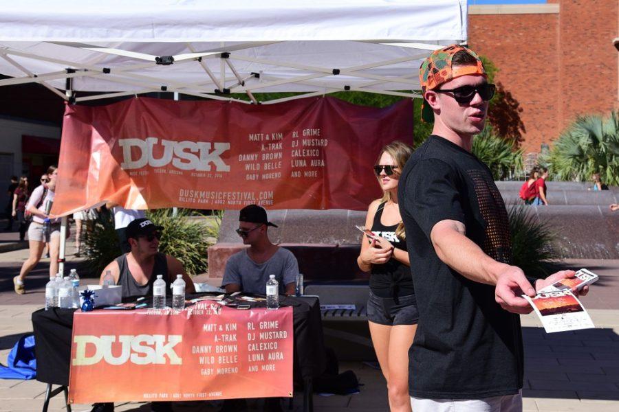 Ambassador Emery Payne passes out flyers in front of the Dusk Music Festival booth on the mall on Wednesday, Oct. 19, 2016. The music festival will take place on Saturday, Oct. 22 at Rillito Park and will feature both local and internationally acclaimed musicians. 