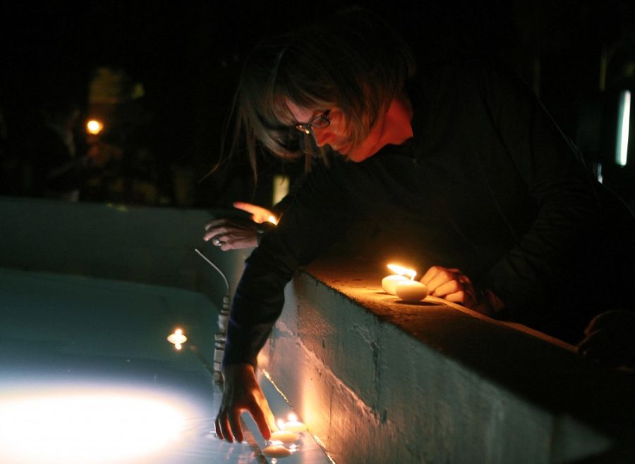 A participant in the Transgender Day of Remembrance vigil places a lit candle in the Old Main fountain Sunday, Nov. 20 in remembrance of those who have been killed and targeted for being transgender.