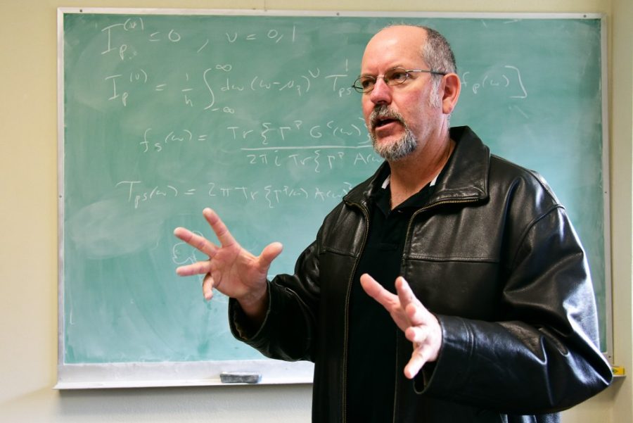 Physics professor Charles Stafford poses for a picture in front of an equation that sets up the principals to define a temperature of something that is in a very extreme state in his office in the Physics and Atmospheric Sciences building on Thursday, Jan. 5, 2017. Stafford has taught at the UA since 1998. 