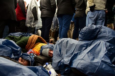 University of Arizona political science and Russian cultures major Courtney Niegoski, center, naps in a plastic rain poncho in damp and chilly conditions with friends hours before the inauguration of President Donald Trump in Washington D.C. on Friday, Jan. 20, 2017. Doors to the inauguration opened at 6 a.m. while Trump did not make an appearance until 11:45. (Photograph by Rebecca Noble)