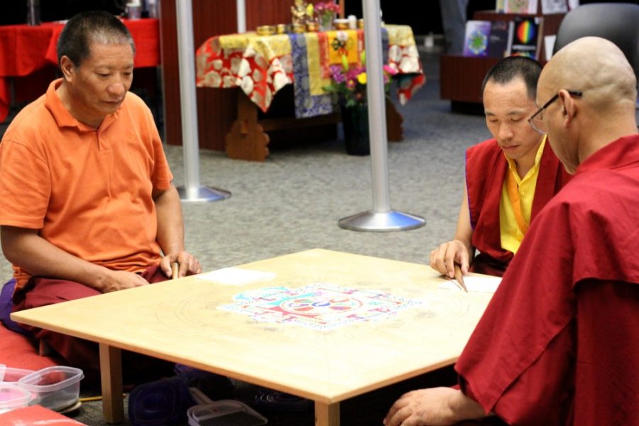Drupe Thinley assisted by Lama Tensin and Lama Norbu apply sand to their mandala as part of a Tibetan Buddhist tradition on April 3, 2017 at the UA library. The mandala will be washed away after it is completed on Thursday, April 6.