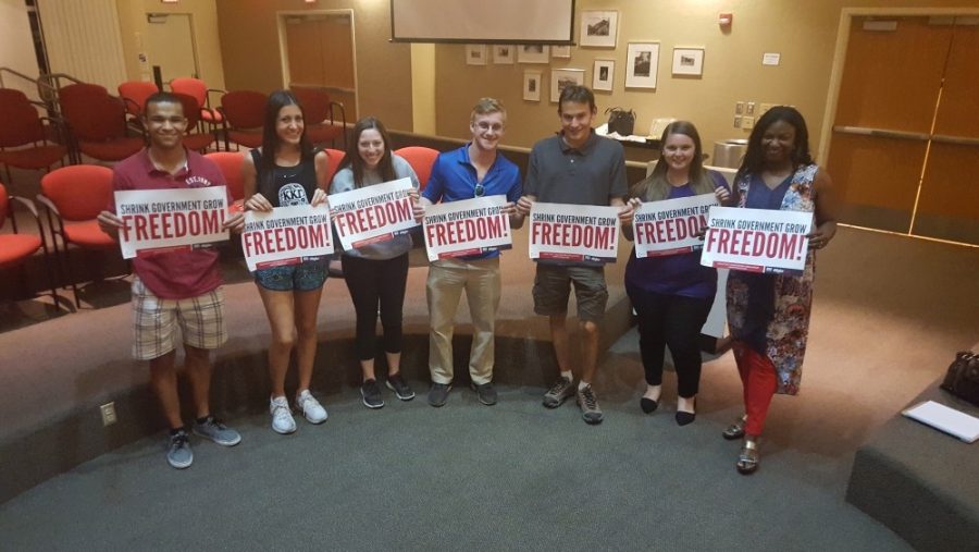The Turning Point USA club members hold signs showing their opposition to big government. Members of the club participated in a panel about free speech on April 19 hosted by the Ayn Rand Institute. 