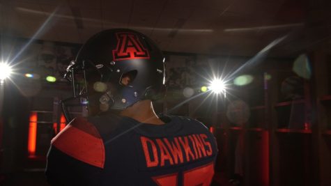 Arizona quarterback Brandon Dawkins showcases the changes in the helmets and jersey backs of the new football uniforms.