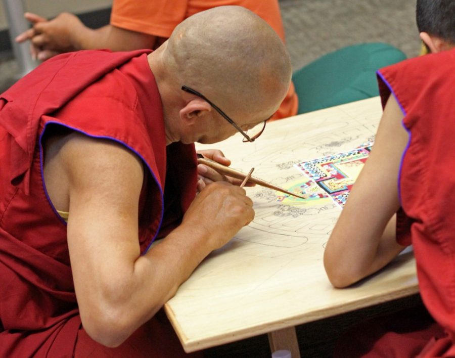 Lama Tensin and Lama Norbu apply sand to their mandala as part of a Tibetan Buddhist tradition on April 3, 2017 at the UA library. The mandala will be washed away after it is completed on Thursday, April 6.