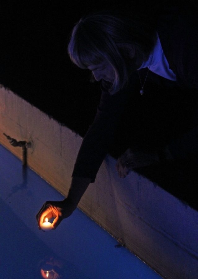 <p>Alex Kelser places a candle in the fountain outside Old Main during Transgender Remembrance Day on Nov. 16. Kelser, among others, placed multiple candles in the water to remember the lives lost.</p>