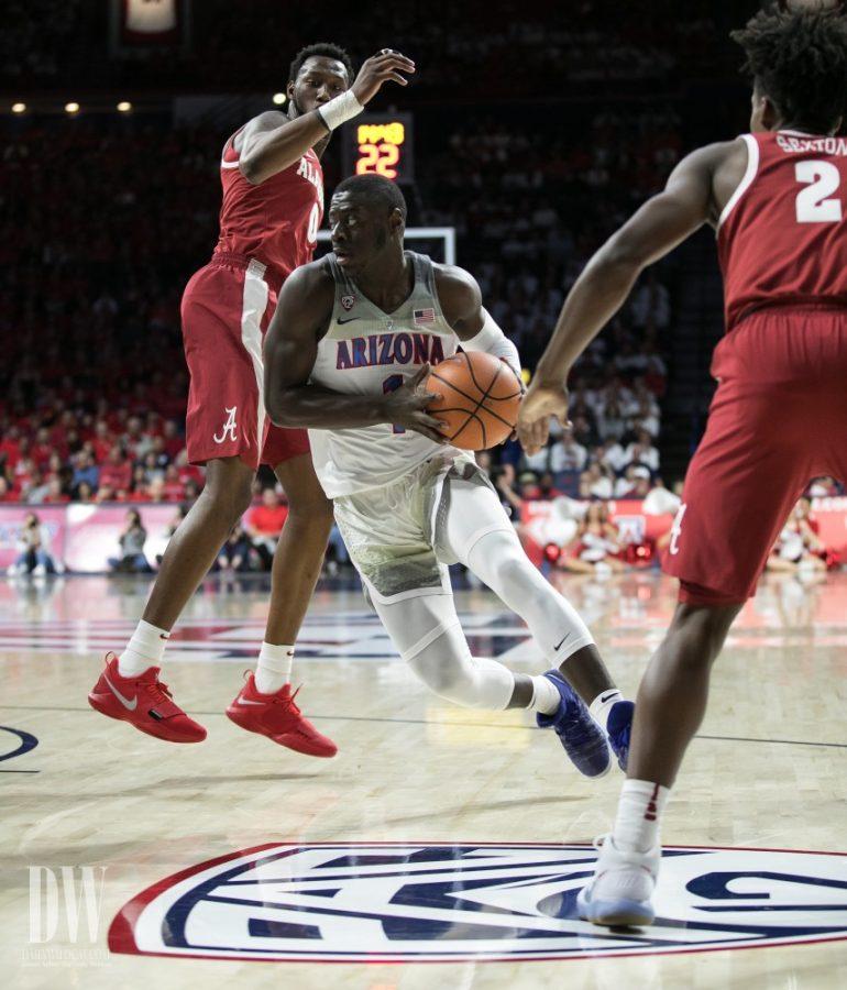 In his season debut, Arizonas Rawle Alkins dribbles past two Alabama defenders to try and score. At the half, Alkins has 1 point. 