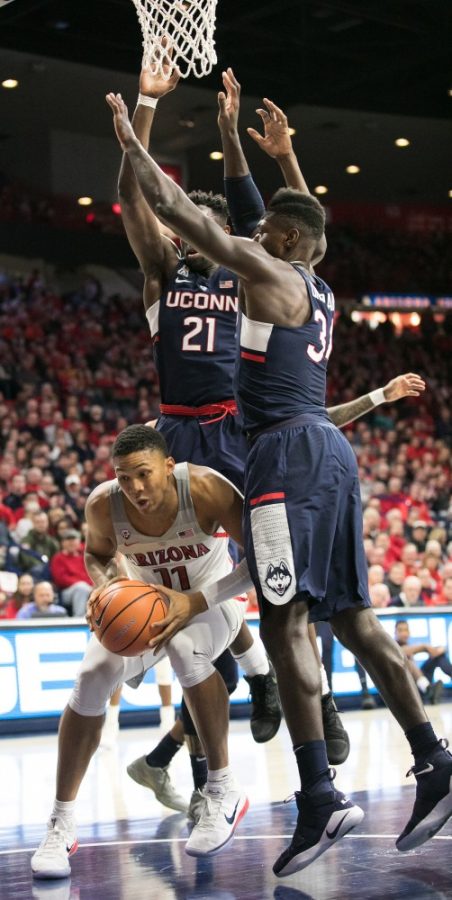 Arizonas Ira Lee (11) pauses while UConns Mamadou Diarra (21) and David Onuorah (34) reach for a block that isnt there.