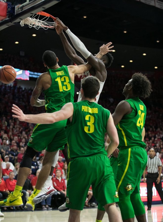 Arizonas Deandre Ayton dunks the ball, despite Oregons Paul White (13)  throwing a hand in his face. White fouled out late in the Arizona-Oregon game.