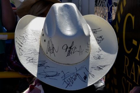 A young boy shows off his cowboy hat which has been signed by some of the best riders in world. Whenever he goes to a rodeo, the young boy asks the winner of certain competitions to sign his hat. So far, he has twenty signatures.