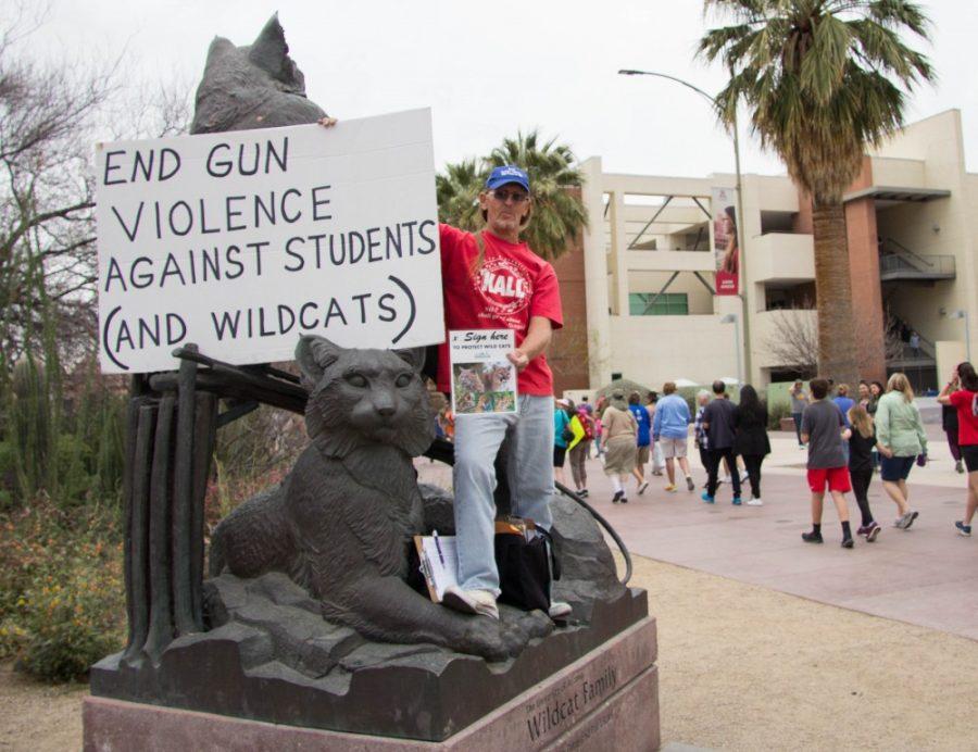 Gary Vella stands on the Wildcat statue holding a sign for all to see during the March for our Lives protest on March 24, 2018 at the UA Mall in Tucson, Ariz.