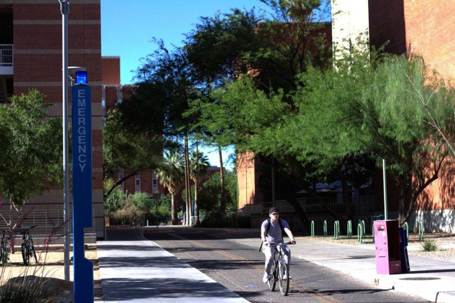 A+student+pedals+past+an+Emergency+Blue+Light+Telephone+located+on+the+UA+Campus+on+May+15%2C+2018.+The+tall%2C+bright-blue+telephones+are+meant+to+stand+at+a+visible+distance+from+each+other+around+campus.+%26nbsp%3B
