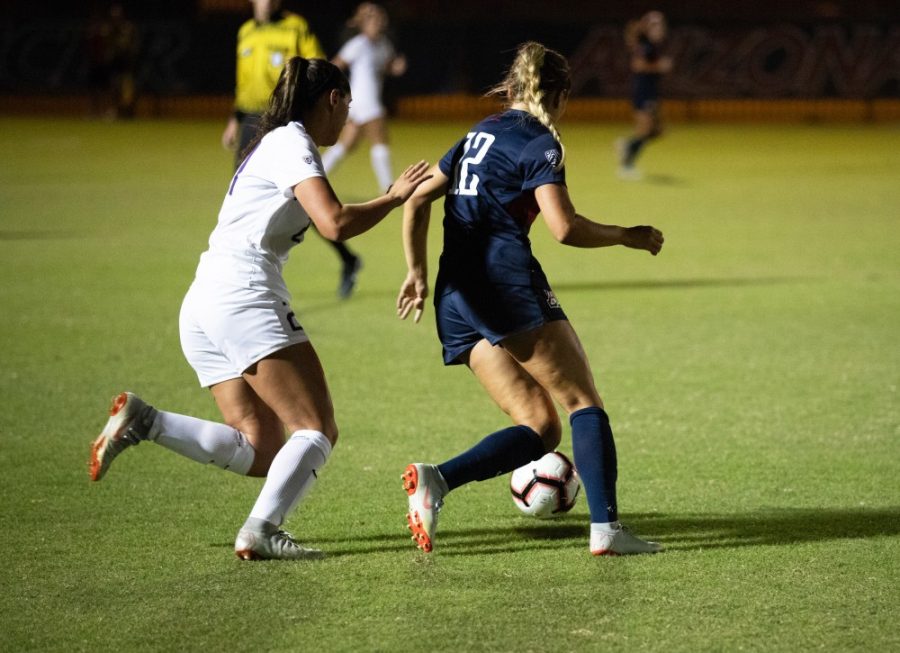 Arizona womens soccer player Kennedy Kieneker (12) guards a Huskie opponent from the ball in the Arizona-Washington game at Murphy Stadium on Thursday, October 18, 2018, in Tucson, AZ. The Wildcats won the game 1-0 in double overtime.