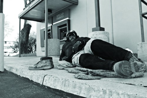 A homeless man lies in front of a Wells Fargo ATM near the University of Arizona. In Tucson, a handful of programs assist the countys 1,380 homeless individuals.