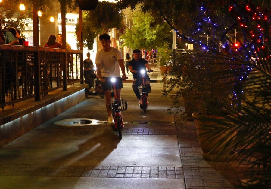 Students riding scooters on University Blvd in front of Gentle Bens Brewing during the pandemic at the University of Arizona in Tucson, Ariz., Tuesday, Oct. 6, 2020.