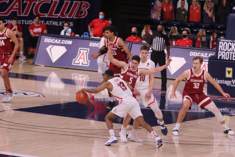 Arizona Wildcat James Akinjo, 13, dribbles the ball past Stanford Cardinal Michael O’Connell, 5, on Thursday, Jan. 28.
