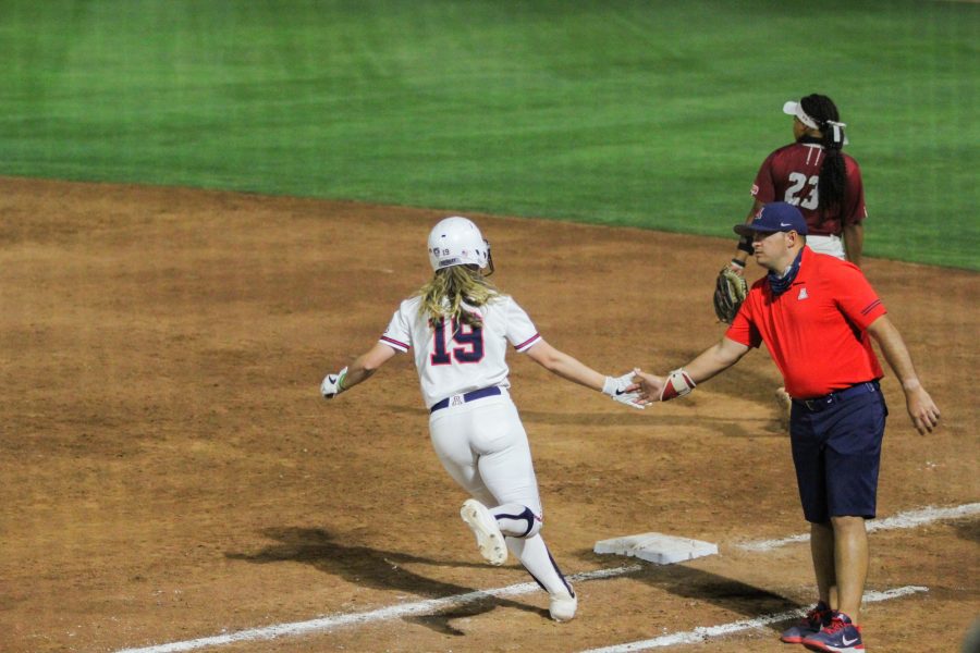 Jessie Harper high fives her coach as she runs through first base. Arizona Softball defeated New Mexico State on Friday, April 9 in Tucson, Ariz.