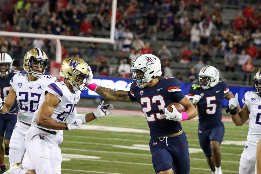 Stevie Rocker Jr. (23), a freshman on the University of Arizona football team, breaks a big run to the outside of the field and stiff arms a University of Washington defender on Oct. 22 at Arizona Stadium. The Wildcats went into halftime up 13-0.