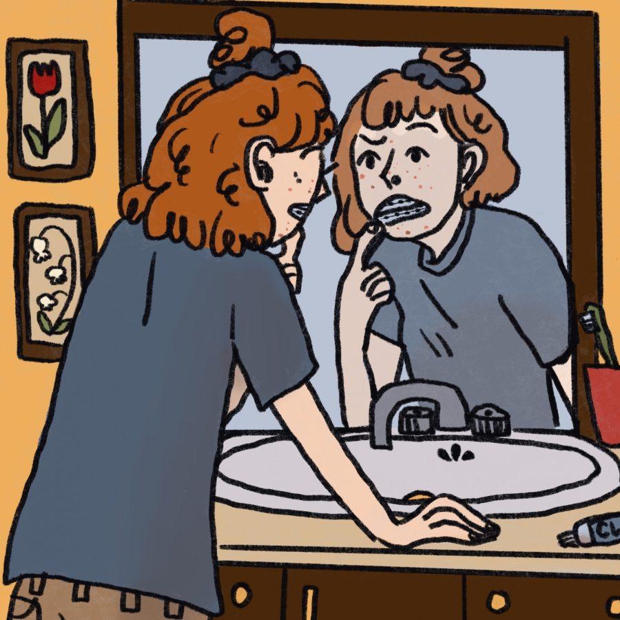 Teenage girl with braces stands in front of mirror and inspects face. 