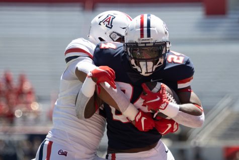 Arizona running back, Jonah Coleman (24), runs with the ball as a defender tackles him at Arizona Stadium on April 9. Arizona held its annual spring game in which Arizona players faced off against one another.  