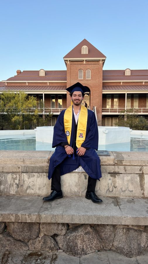Matheo Herrera sits on the fountain outside of Old Main for his graduation pictures. (Courtesy photo of Tala Holayel)