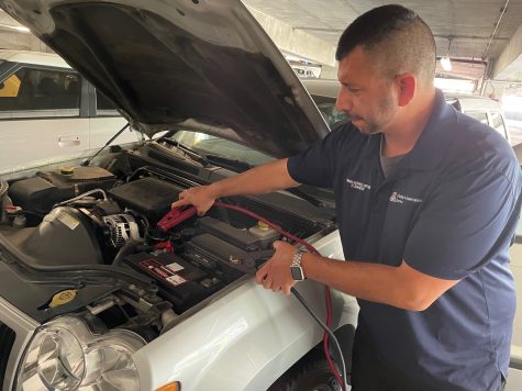 Hector Bandin, a parking services officer with the Motorist Assistance Program, prepares to jump start a battery at the University of Arizona on March 28. (Photo by Joseph Flores, El Inde Arizona)