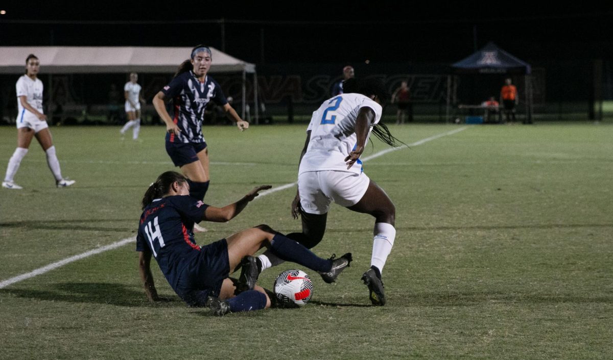 Sami Baytosh (14) slides under UCLAS Ayo Oke (2) during the first half of the game on Thursday, Oct. 19 Tucson on Murphey Field at Mulcahy Stadium. During the first half, the score was tied at 1-1.