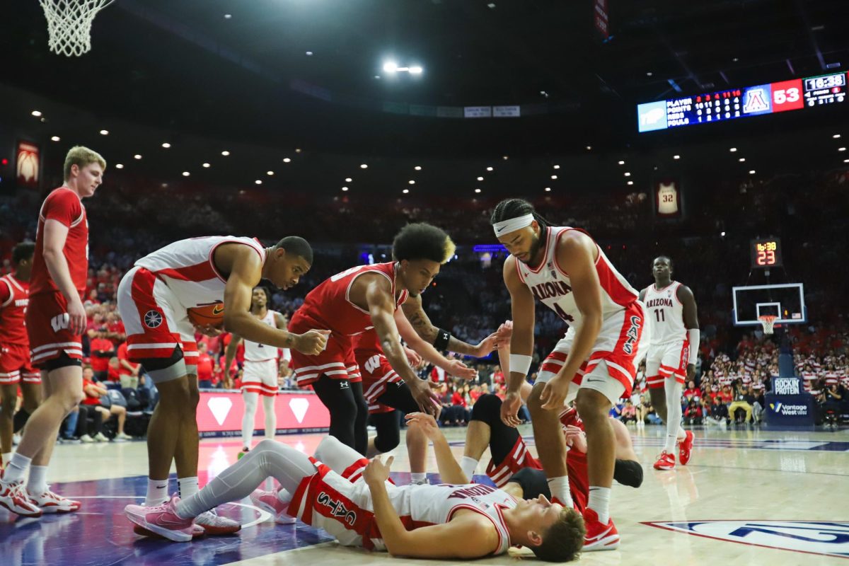 Players from both Arizona and Wisconsin help their teammates up after a messy foul by Wisconsin in McKale Center on Dec. 9. Both teams finished the game with an equal 34 fouls a piece.
