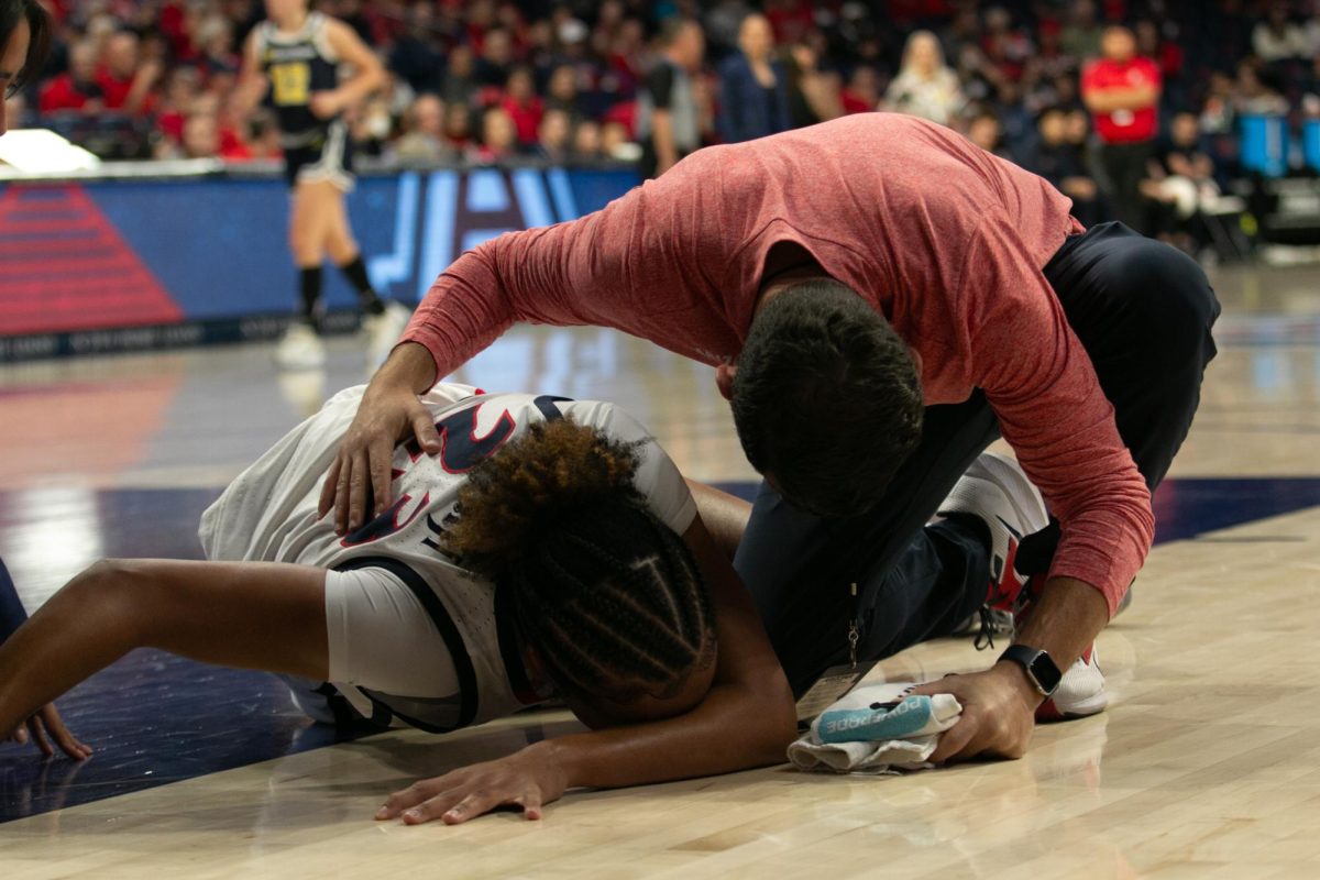 Wildcats forward Maya Nnaji is comforted by coaching staff after a leg injury during the women's basketball game against UC San Diego in McKale Center on Dec. 7. The play continued for some time after her injury before stopping until she could get off the court.
