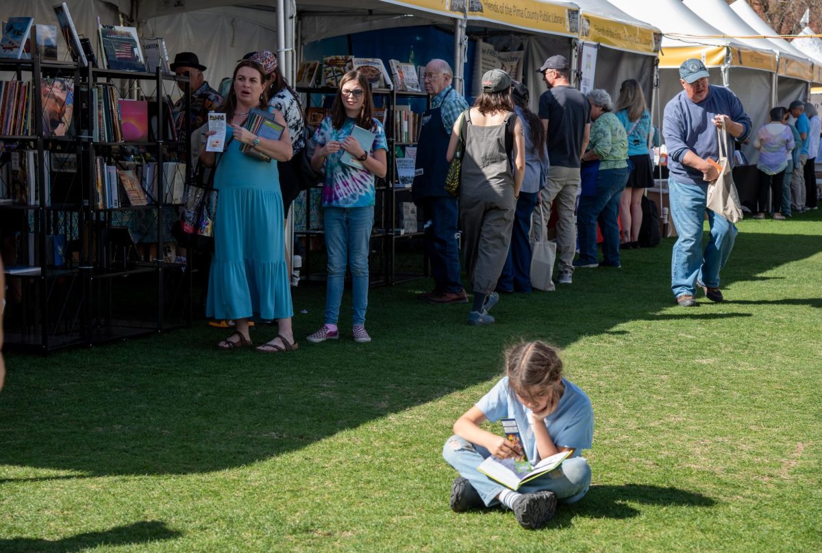 A+child+reads+a+book+on+the+grass+at+the+Tucson+Festival+of+Books+on+March+10.+The+Tucson+Festival+of+Books+offered+something+for+every+age.