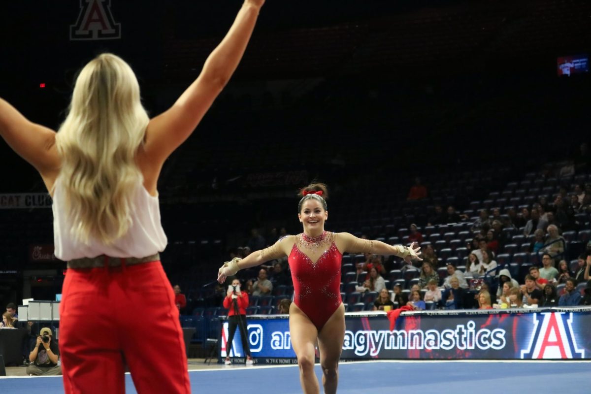 GymCats associate head coach Taylor Spears cheers for Caroline Herry as she finishes her floor routine in McKale Center on March 13. Herry scored the highest on floor for the team, with an average of 9.875.
