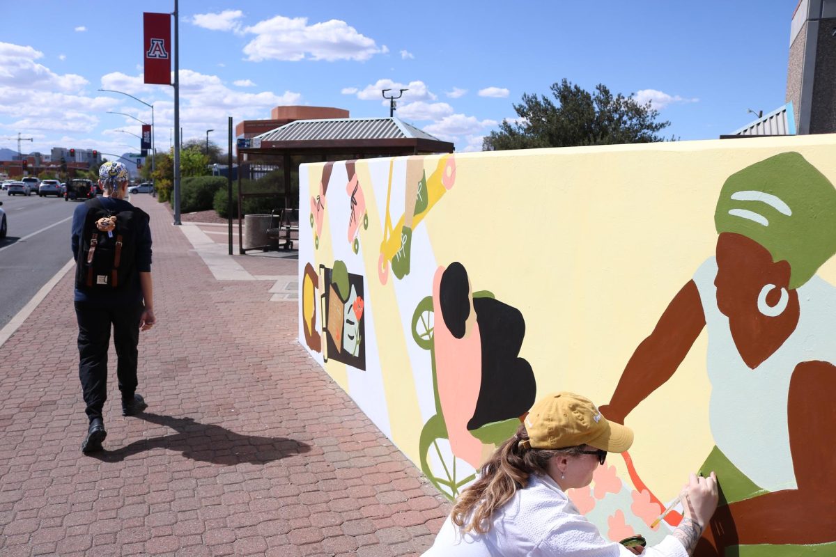 Lexi Watins helps paint a mural as part of the Speedway Corridor Mural Project on March 20. Monique Laraway, the artist of the mural, incorporated themes of urban inclusivity and safe streets.
