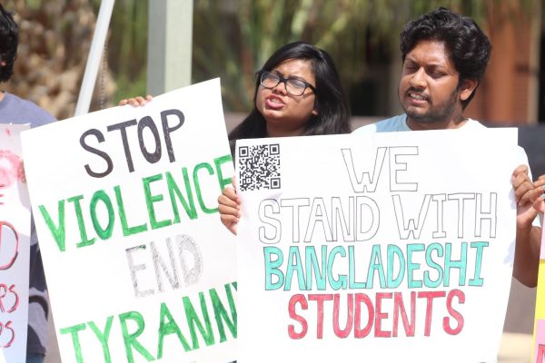 Two protesters chant while holding protest posters on July 24. The QR code on the poster leads to a New York Times article titled Bangladesh Deploys Border Force to Try to Quell Student Protests.