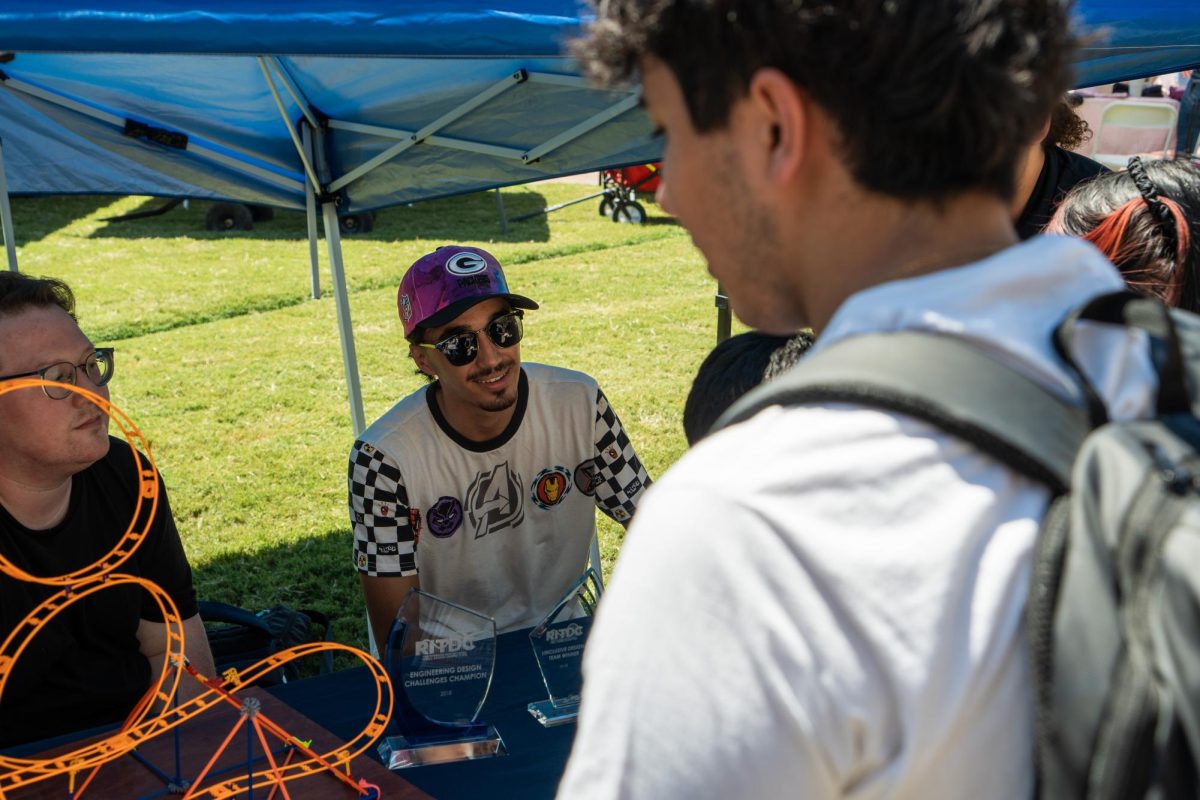 Chayse Innis, project coordinator of the University of Arizona's Theme Park Entertainment Group (TPEG), converses with an interested student at the ASUA Club Fair on Sept. 5. UA's TPEG offers those who are interested in themed entertainment related projects an opportunity to work with other students who share the same passion.