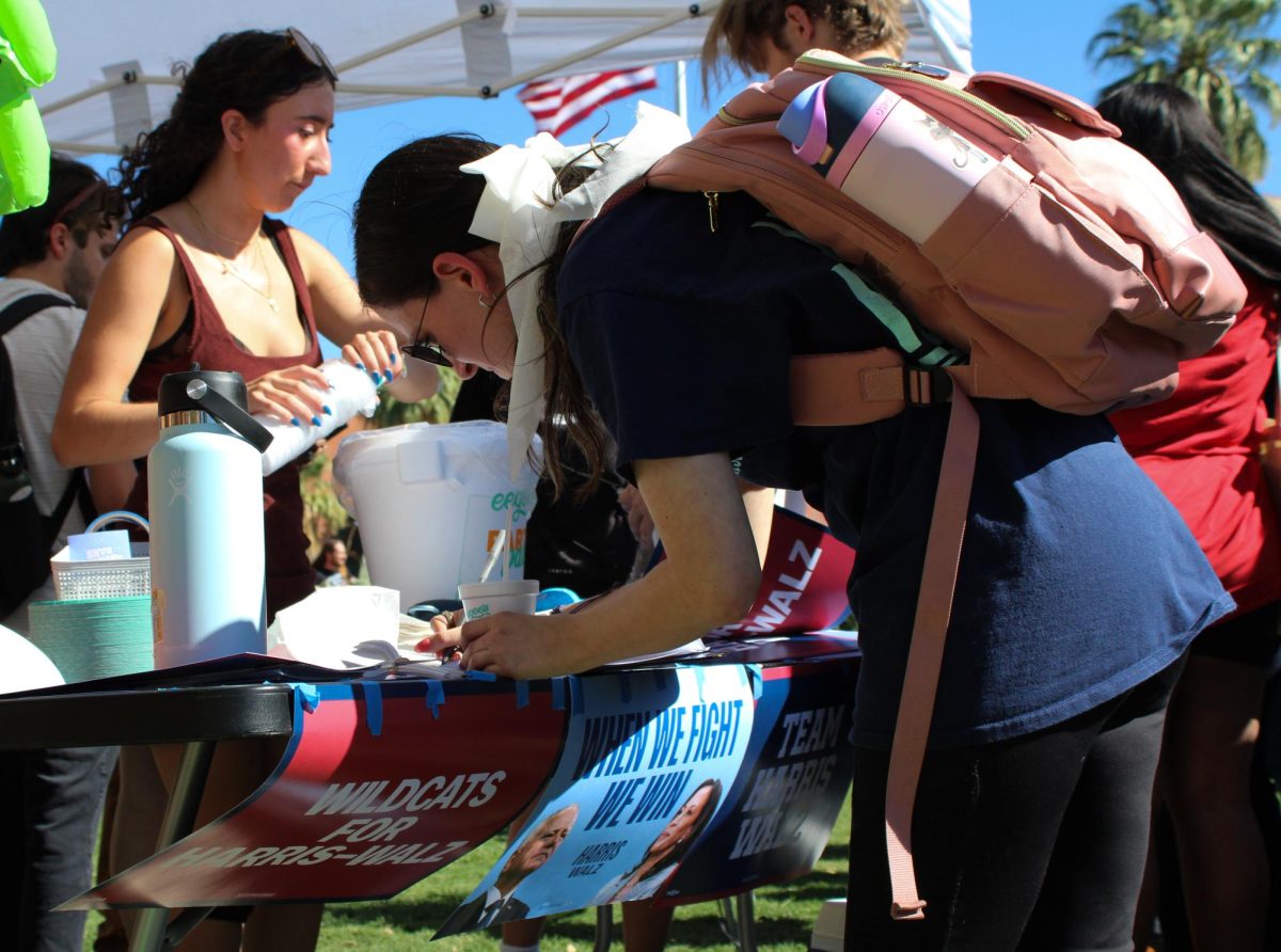 A student signs up to register to vote on Oct. 15 on the University of Arizona campus Mall. U.S. Senator for Arizona had a meet and greet with students encouraging them to vote.