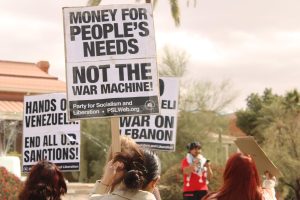 Protestors hold signs during a protest at  Old Main on Feb. 14. The protesters focused on sanctions on Venezuela as well as the war in Gaza.