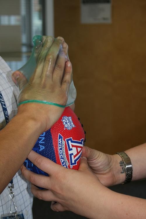 Erin Strange, specialist in Violence Prevention and an intern Ralphie Esperas, a Health Education Major, demonstrate putting a condom on a football at the Health Promotion & Preventive Services Center. This is a method used by Lee Ann Hamilton, Health Educator and Sexual Health Specialist, to teach students how to properly put on a condom.