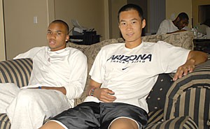 Track sprinters Marcus Tyus, left, from Virginia, and Xuehan Xiong from China sit on a couch in their house. The two roommates barely talked their first two weeks, but said they have since become like family. 
