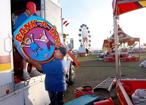 Mark Terry, left, and Mario Sanchez, employees of Ray Cammack Shows, set up one of the carnival booths for Spring Fling yesterday evening. Spring Fling begins today and runs through Sunday.
