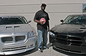UA thrower Korion Morris poses with a discus Thursday outside C/3 Motorsports, where he works. He personalized the car on the right, which he owns. The car on left is a custom-designed company car.