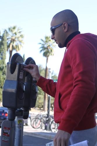 Bader Alsuhaim, an engineering student, puts money in a meter before heading to class Thursday. New meters with a credit card swipe will soon be installed around the campus.