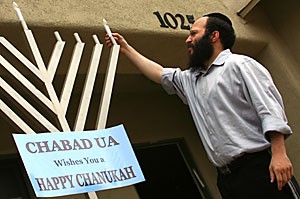 Rabbi Yosef Winner, co-director of the UA Chabad Jewish Student Center lights up the first light of Hanukkah on Friday afternoon in front of the Chabad house on North Euclid Avenue.