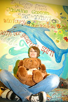 Tu Nidito volunteer and facilitator Dawn Kossmann sits below a mural honoring a former member yesterday at the Tu Nidito childrens center. Tu Nidito is a nonprofit organization that assists children and families with life-threatening illnesses.
